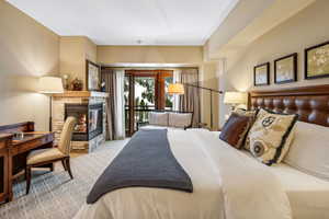 Carpeted bedroom featuring access to exterior and a fireplace