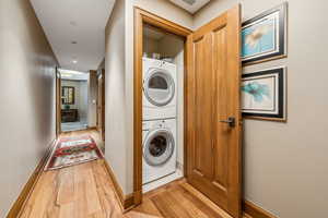 Washroom featuring light hardwood / wood-style flooring and stacked washer and clothes dryer