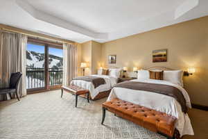 Carpeted bedroom featuring access to outside, a mountain view, and a tray ceiling