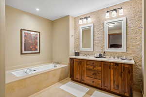 Bathroom featuring tile patterned flooring, vanity, and tiled tub