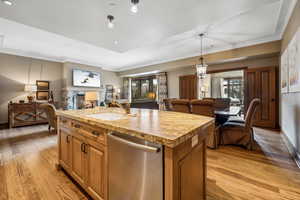 Kitchen with dishwasher, an island with sink, plenty of natural light, and light wood-type flooring