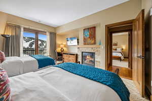 Bedroom featuring wood-type flooring, access to outside, and a stone fireplace