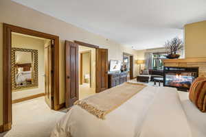 Carpeted bedroom featuring a fireplace and ensuite bath