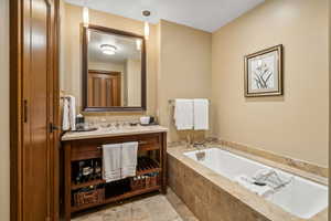 Bathroom featuring tiled tub and vanity