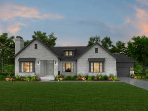 View of front facade featuring a garage and a yard