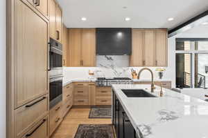 Kitchen featuring sink, light stone counters, extractor fan, light hardwood / wood-style floors, and light brown cabinetry