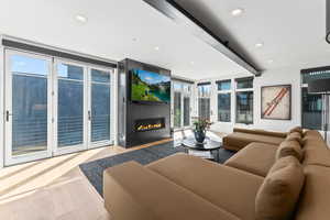 Living room with plenty of natural light, floor to ceiling windows, light wood-type flooring, and a fireplace