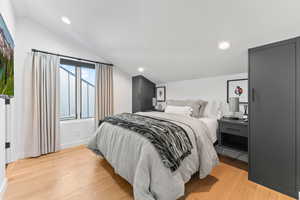 Bedroom featuring light wood-type flooring and vaulted ceiling