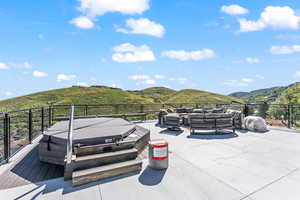 View of patio featuring a hot tub, a mountain view, and an outdoor living space