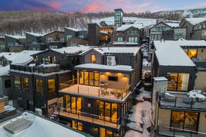 Snow covered rear of property with a balcony