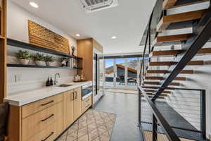 Bar with light tile patterned flooring, a wall of windows, sink, and light brown cabinets