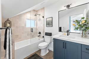 Full bathroom featuring combined bath / shower with glass door, tile patterned floors, toilet, and lofted ceiling