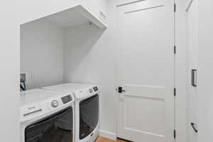 Washroom featuring light wood-type flooring and washing machine and clothes dryer