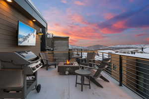 Snow covered patio featuring grilling area and an outdoor fire pit