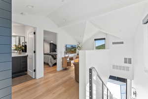 Hallway featuring vaulted ceiling and light hardwood / wood-style flooring