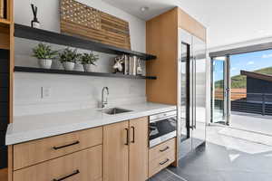 Kitchen featuring light brown cabinets, light stone counters, and sink