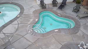 View of pool with an in ground hot tub and a patio