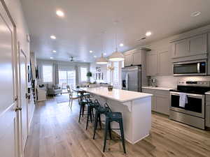 Kitchen featuring light wood-type flooring, stainless steel appliances, gray cabinets, and a kitchen island