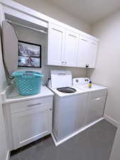 Laundry area with cabinets, dark tile patterned floors, and washer and dryer