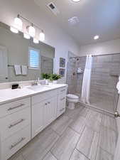 Bathroom featuring a shower with shower curtain, vanity, and toilet