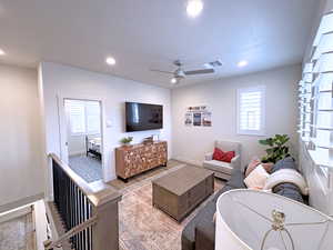 Living room featuring light wood-type flooring, ceiling fan, and a healthy amount of sunlight