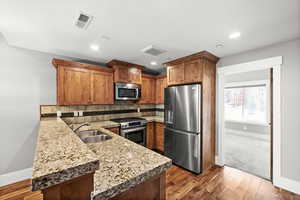 Kitchen with kitchen peninsula, hardwood / wood-style floors, stainless steel appliances, and sink