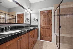 Bathroom with tile patterned floors, vanity, and a shower with shower door