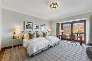 Bedroom featuring hardwood / wood-style flooring, access to exterior, and ornamental molding