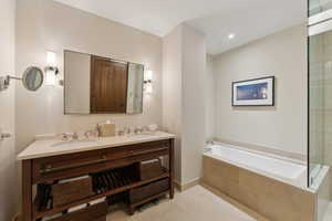 Bathroom with tiled bath, tile patterned flooring, and vanity