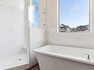 Bathroom with hardwood / wood-style floors, plus walk in shower, and tile walls