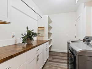 Laundry room featuring washing machine and dryer, dark hardwood / wood-style flooring, and cabinets