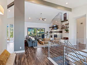 Living room featuring ceiling fan, beam ceiling, hardwood / wood-style flooring, high vaulted ceiling, and a tiled fireplace