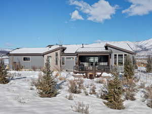 Snow covered back of property featuring a deck with mountain view