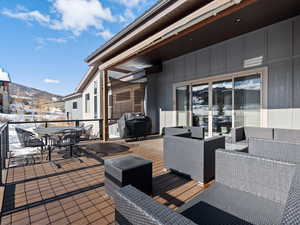 Snow covered deck featuring a mountain view, an outdoor living space, and grilling area