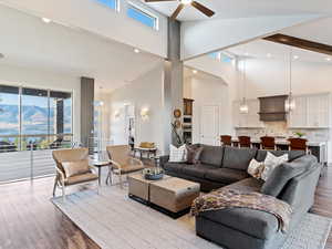 Living room with beamed ceiling, ceiling fan, light hardwood / wood-style floors, and high vaulted ceiling