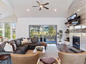 Living room featuring a fireplace, ceiling fan, hardwood / wood-style floors, and vaulted ceiling