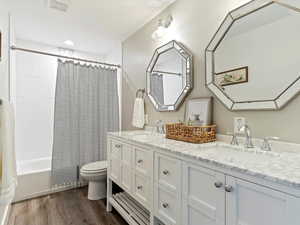 Full bathroom featuring hardwood / wood-style floors, vanity, toilet, and shower / bath combination with curtain