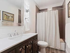 Full bathroom featuring wood-type flooring, vanity, toilet, and shower / bath combo with shower curtain