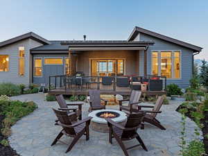 Rear view of property featuring a patio, an outdoor fire pit, and a wooden deck