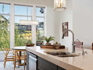 Kitchen with light stone countertops, decorative light fixtures, a healthy amount of sunlight, and sink