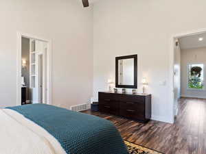 Bedroom featuring ceiling fan, dark hardwood / wood-style flooring, and a high ceiling