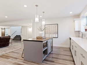 Kitchen with stainless steel appliances, a barn door, light hardwood / wood-style floors, white cabinetry, and hanging light fixtures