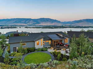 Back house at dusk featuring a lawn and a water and mountain view