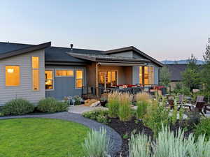 Back house at dusk with a lawn, outdoor lounge area, and a patio