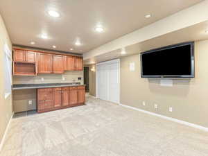 Kitchen with a textured ceiling, built in desk, and light colored carpet