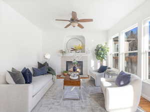 Living room featuring ceiling fan, wood-type flooring, and a tile fireplace