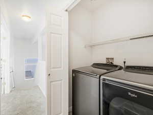 Laundry area featuring washing machine and dryer and carpet