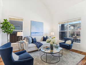 Living room featuring hardwood / wood-style flooring, high vaulted ceiling, and a healthy amount of sunlight