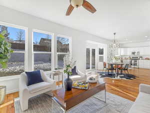 Living room with a healthy amount of sunlight, ceiling fan with notable chandelier, and light wood-type flooring