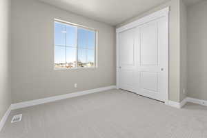 Unfurnished bedroom featuring light carpet and a closet